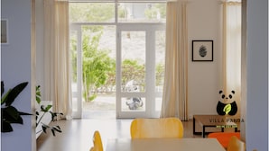 Een kamer met een grote schuifdeur die uitkomt op een tuin, een ingelijst beeld aan de muur, en een bord met het logo van een panda.