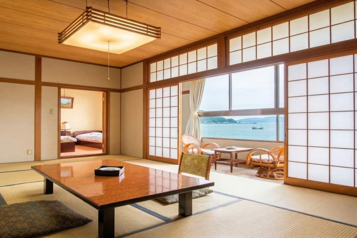 A traditional Japanese room with tatami flooring, a low table, and a view of the sea.