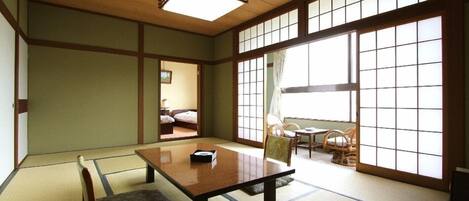 Una habitación japonesa tradicional con suelo de tatami, una mesa baja y puertas correderas.
