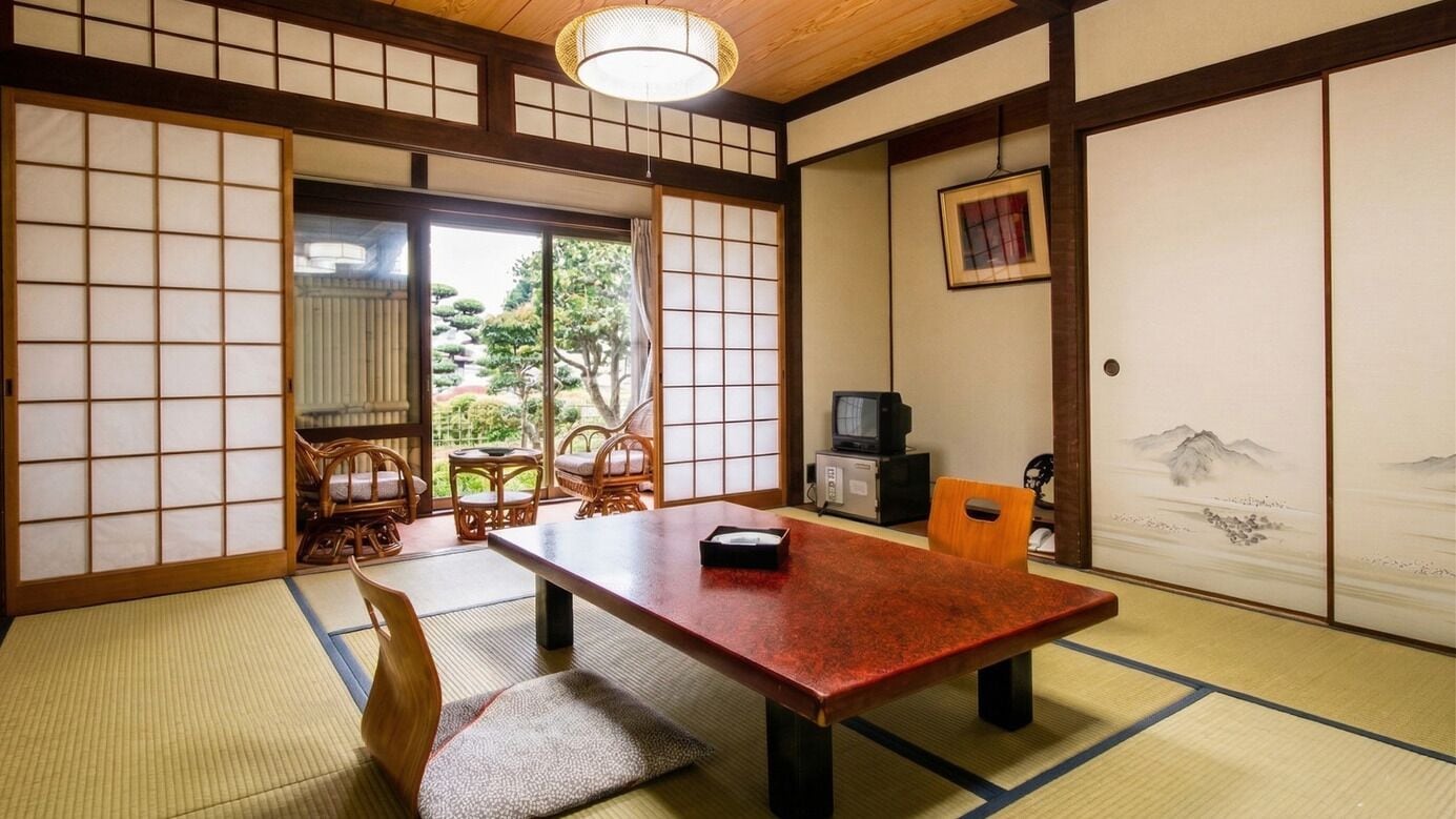 Una habitación japonesa tradicional con suelo de tatami, una mesa baja y puertas correderas.