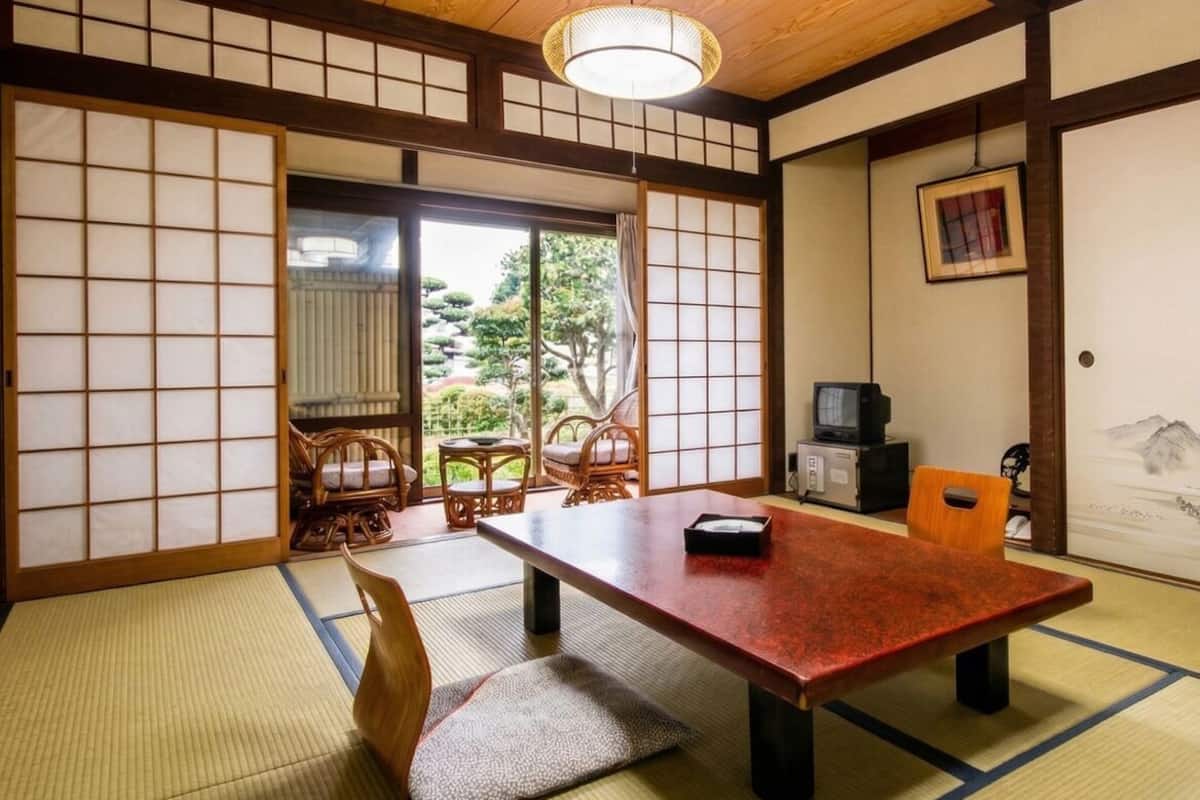 A traditional Japanese room with tatami flooring, a low table, and sliding doors.
