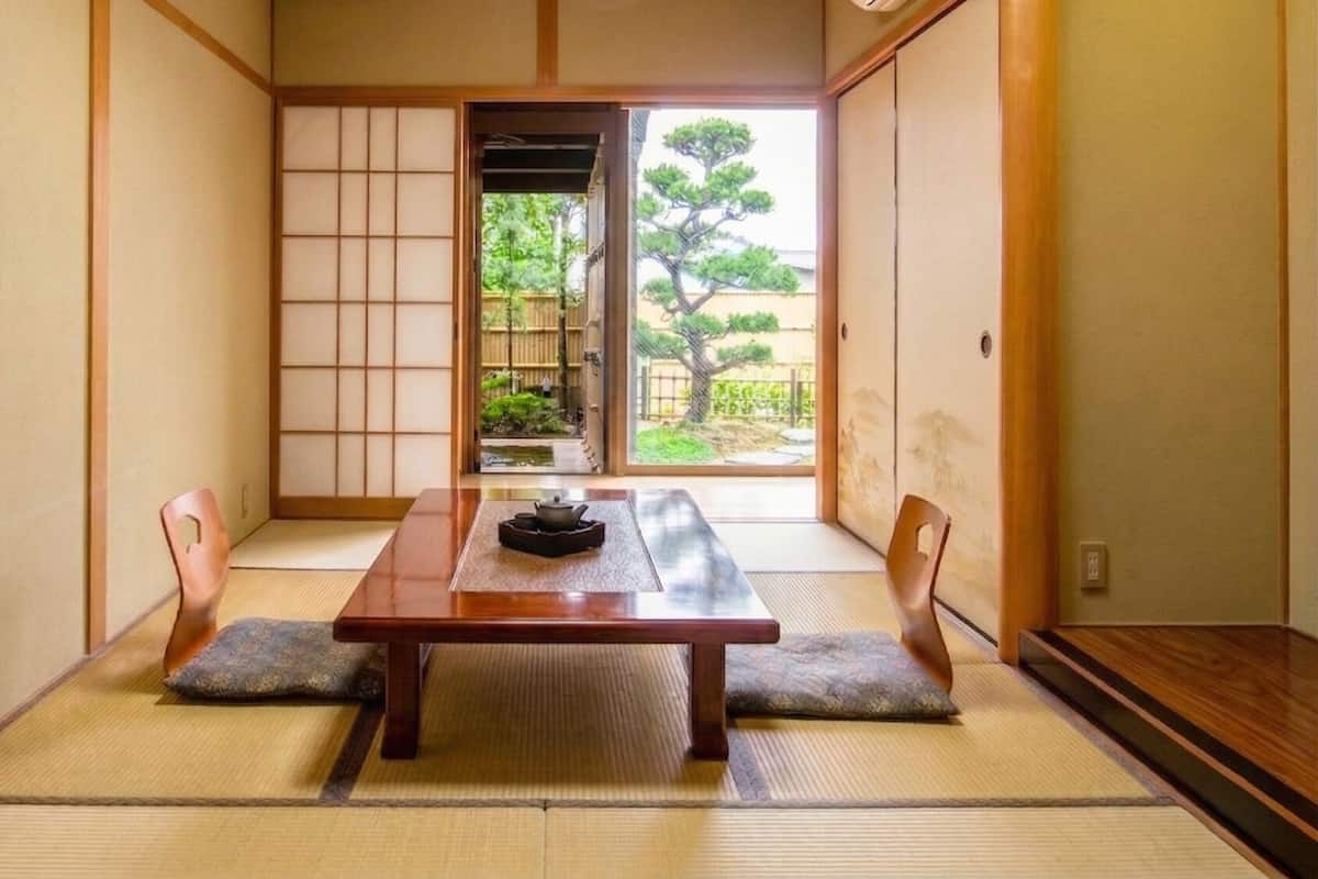 A traditional Japanese room with tatami flooring, a low table, and sliding doors leading to a garden.