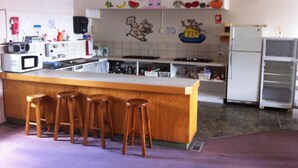 Una cocina con una barra de madera, taburetes, microondas, refrigerador y una pared decorada con personajes de caricaturas.