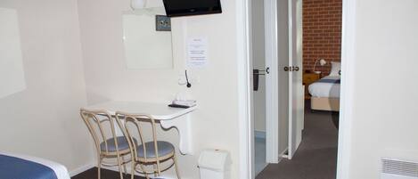 A hotel room with two beds, a desk with a chair, a television, and a door leading to a bathroom.