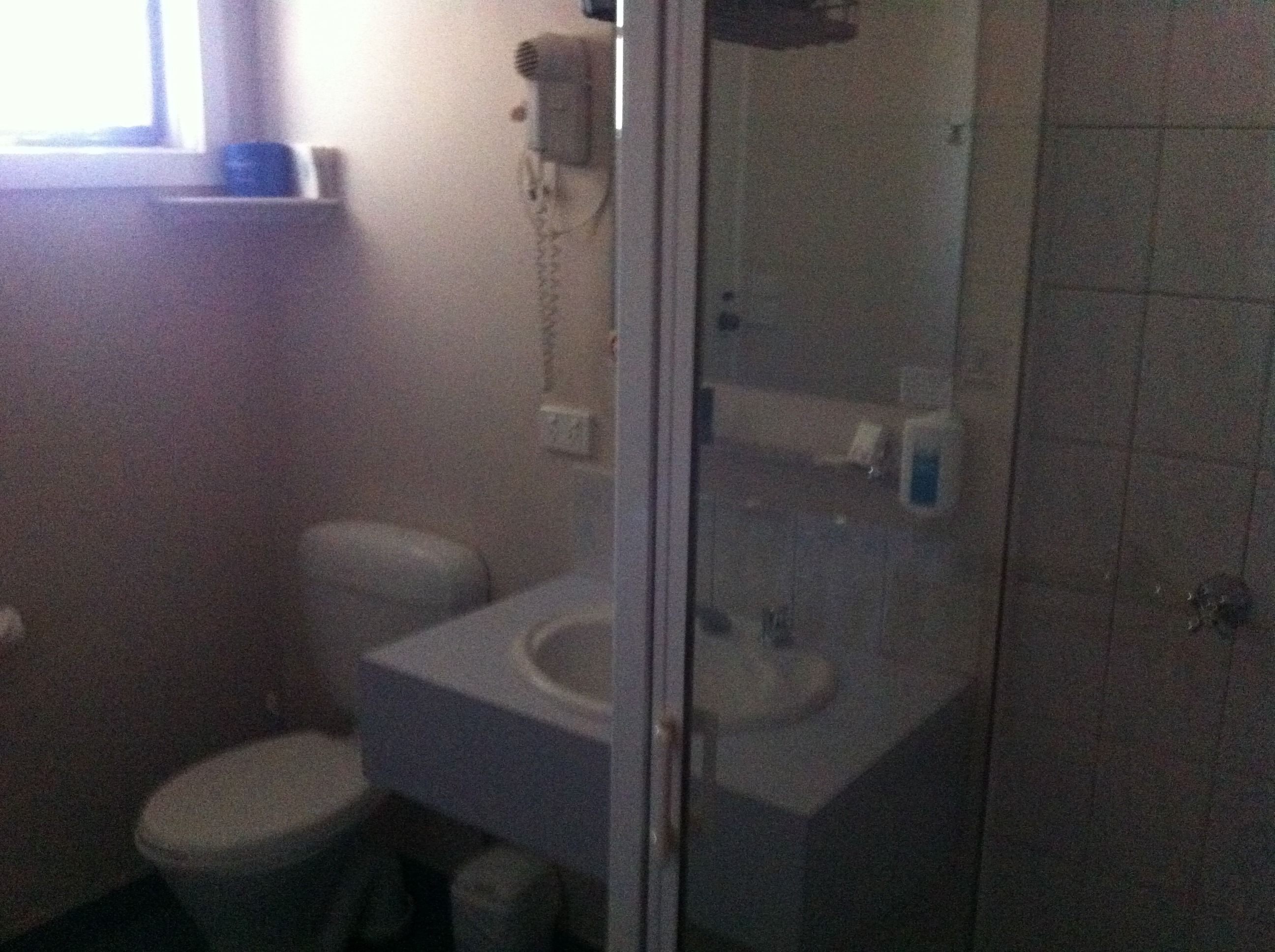 A small bathroom with a toilet, sink, and shower.