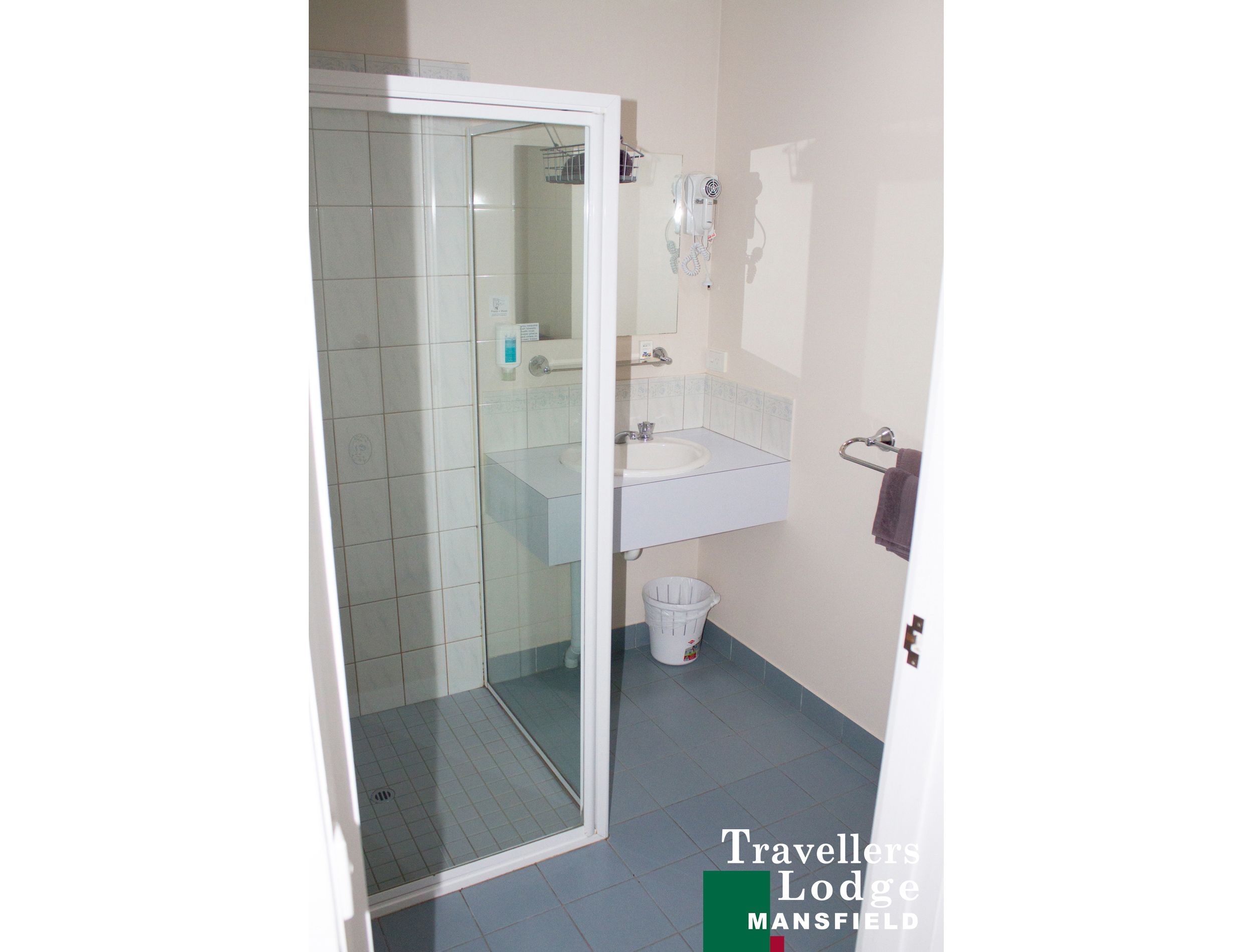 A bathroom with a glass-enclosed shower, a sink, and a towel rack.