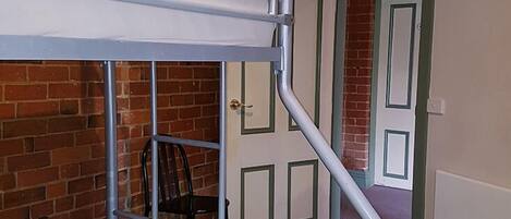 A bunk bed in a room with a brick wall and a door.