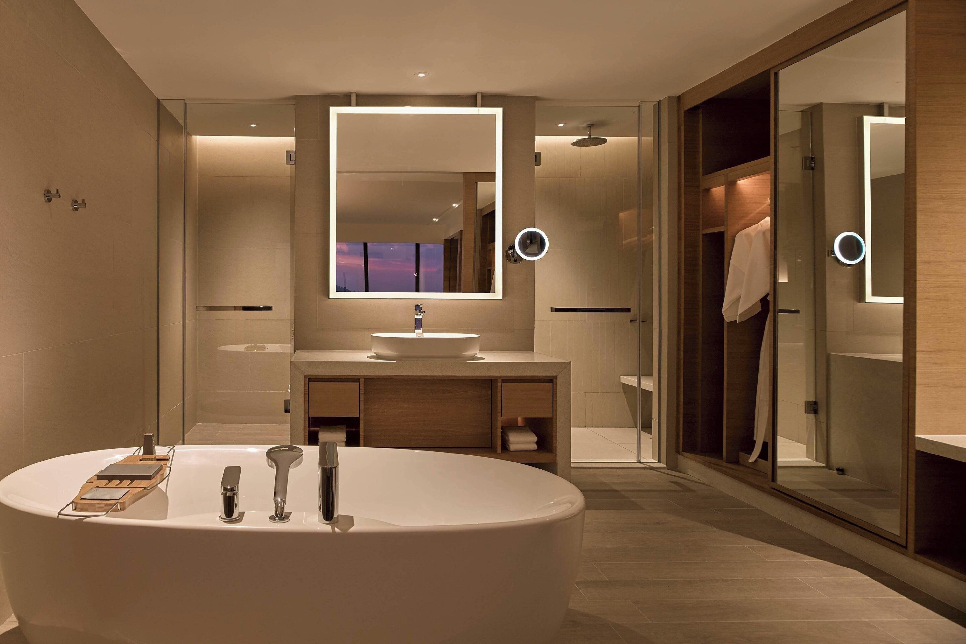 A modern bathroom with a freestanding bathtub, a vanity with a mirror, and a walk-in closet with a sliding door.