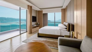 Habitación de hotel moderna con una cama grande, televisión de pantalla plana, sofá y vista al mar.
