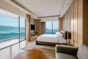 A modern hotel room with a large bed, a flat-screen TV, a sofa, and a view of the sea. - Kota Kinabalu Marriott Hotel (Kota Kinabalu)