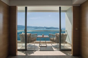 A balcony with a table and chairs, offering a view of the sea and distant land. - Kota Kinabalu Marriott Hotel (Kota Kinabalu)