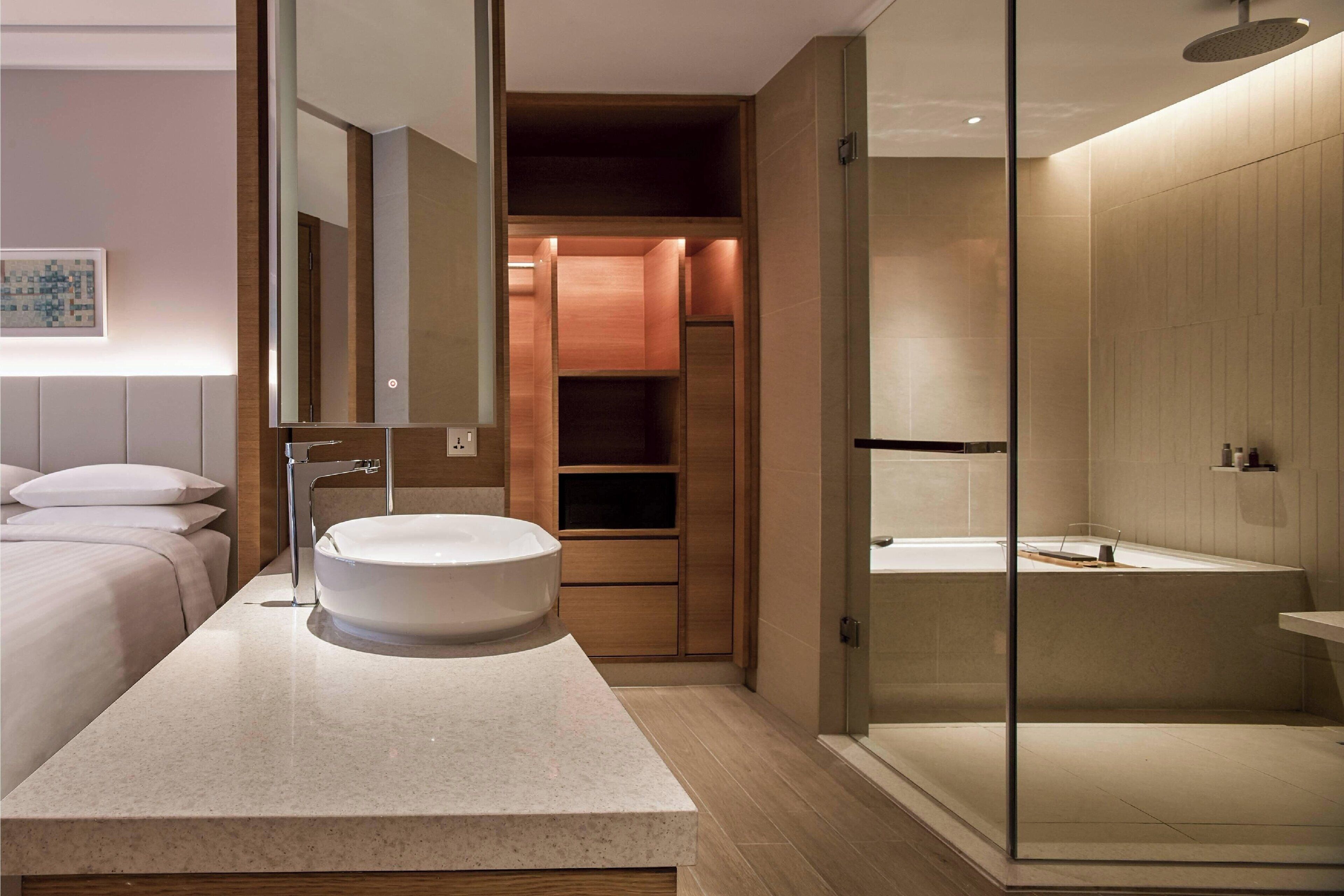 Een moderne badkamer met een ruime wastafel, een douche met glazen wand en een inloopkast.