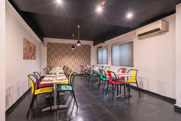 A dining area with multiple tables and chairs, a patterned wall, and an air conditioning unit.