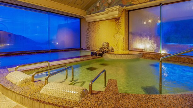 A heated indoor swimming pool with a view of the mountains through large windows. - Yukai Resort Unzen Onsen Unzen Toyokan (Unzen)