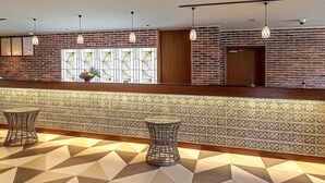A reception area with a brick wall, patterned floor, and hanging pendant lights. - Yukai Resort Unzen Onsen Unzen Toyokan (Unzen)