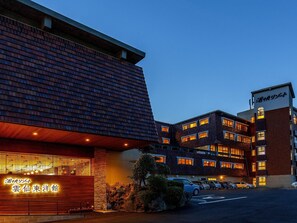 A hotel with a modern brick facade, multiple windows, and a parking lot. - Yukai Resort Unzen Onsen Unzen Toyokan (Unzen)