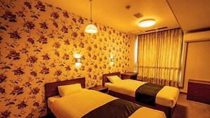 A hotel room with two beds, floral wallpaper, bedside lamps, and a window with curtains. - Yukai Resort Unzen Onsen Unzen Toyokan (Unzen)