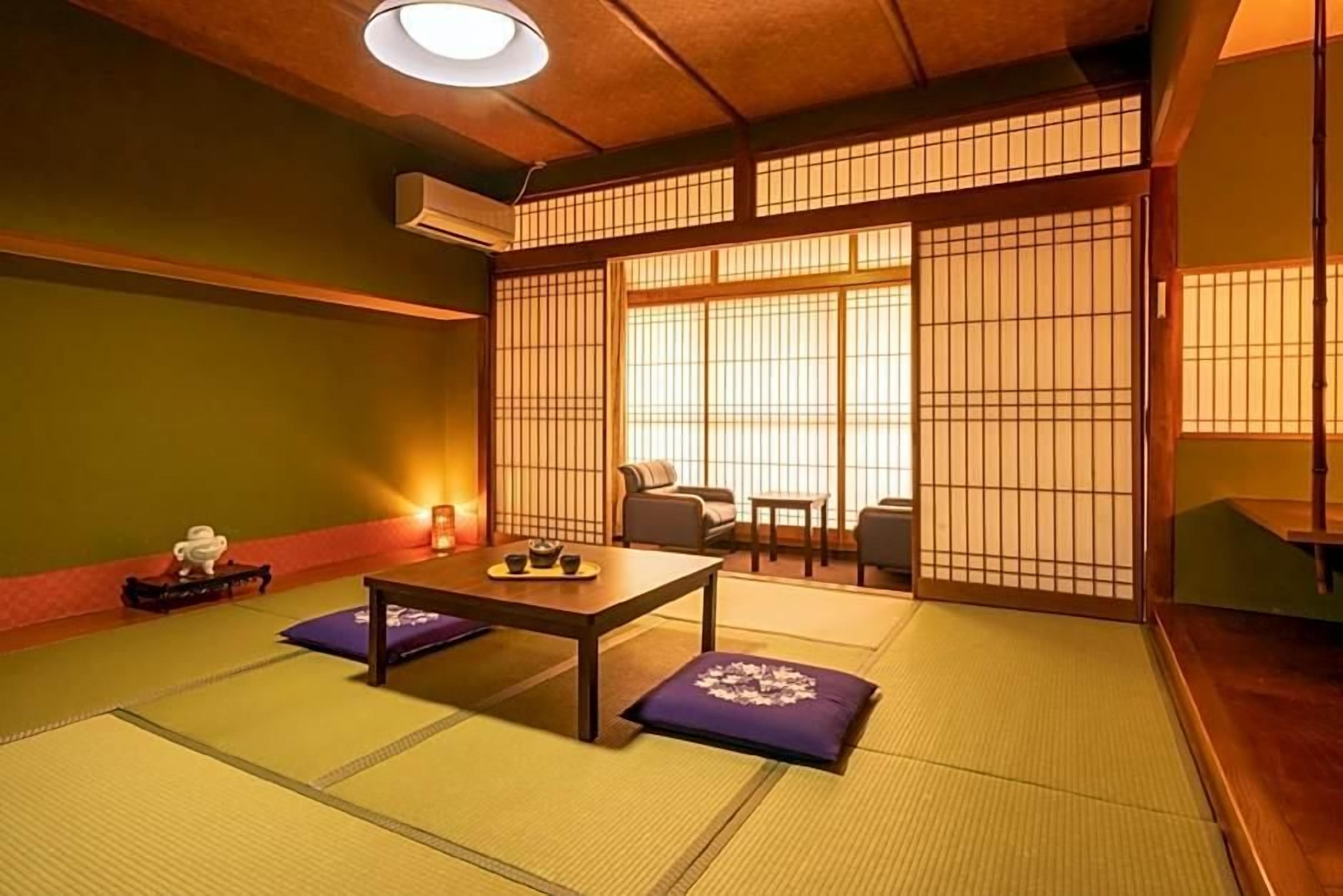 A traditional Japanese room with tatami flooring, a low table with cushions, and sliding shoji doors.