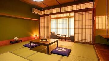 A traditional Japanese room with tatami flooring, a low table with cushions, and sliding shoji doors.