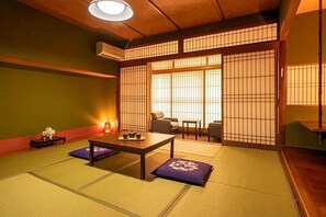 Una habitación tradicional japonesa con suelo de tatami, una mesa baja con cojines y puertas correderas shoji.