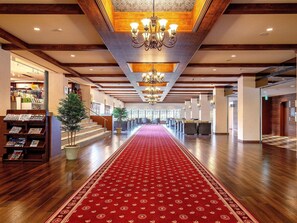 A spacious hotel lobby with a red carpet, wooden floors, and a chandelier. - Yukai Resort Unzen Onsen Unzen Toyokan (Unzen)
