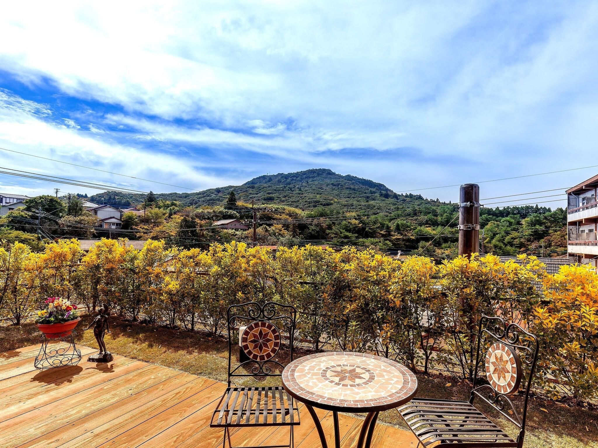 A patio with a metal table and chairs, a decorative metal fence, and a view of a mountain.
