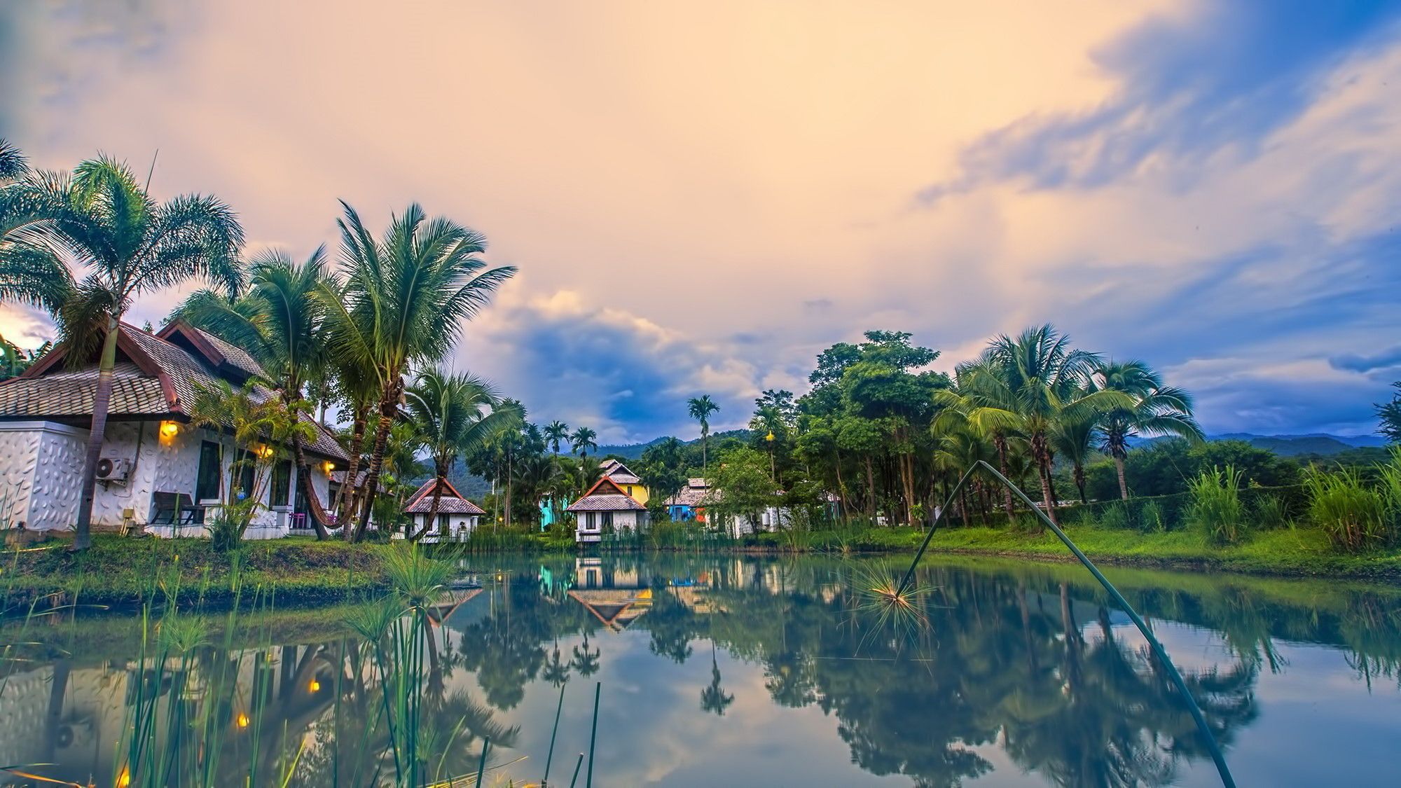 A serene lakeside village with traditional houses and palm trees.