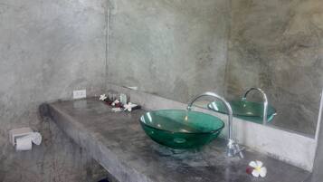 Un bagno con un lavandino in vetro verde, uno specchio e un erogatore di asciugamani.