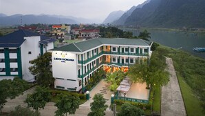 Ein Hotel mit weiß-grüner Fassade, mehreren Etagen und einem Innenhof mit Außenbestuhlung.