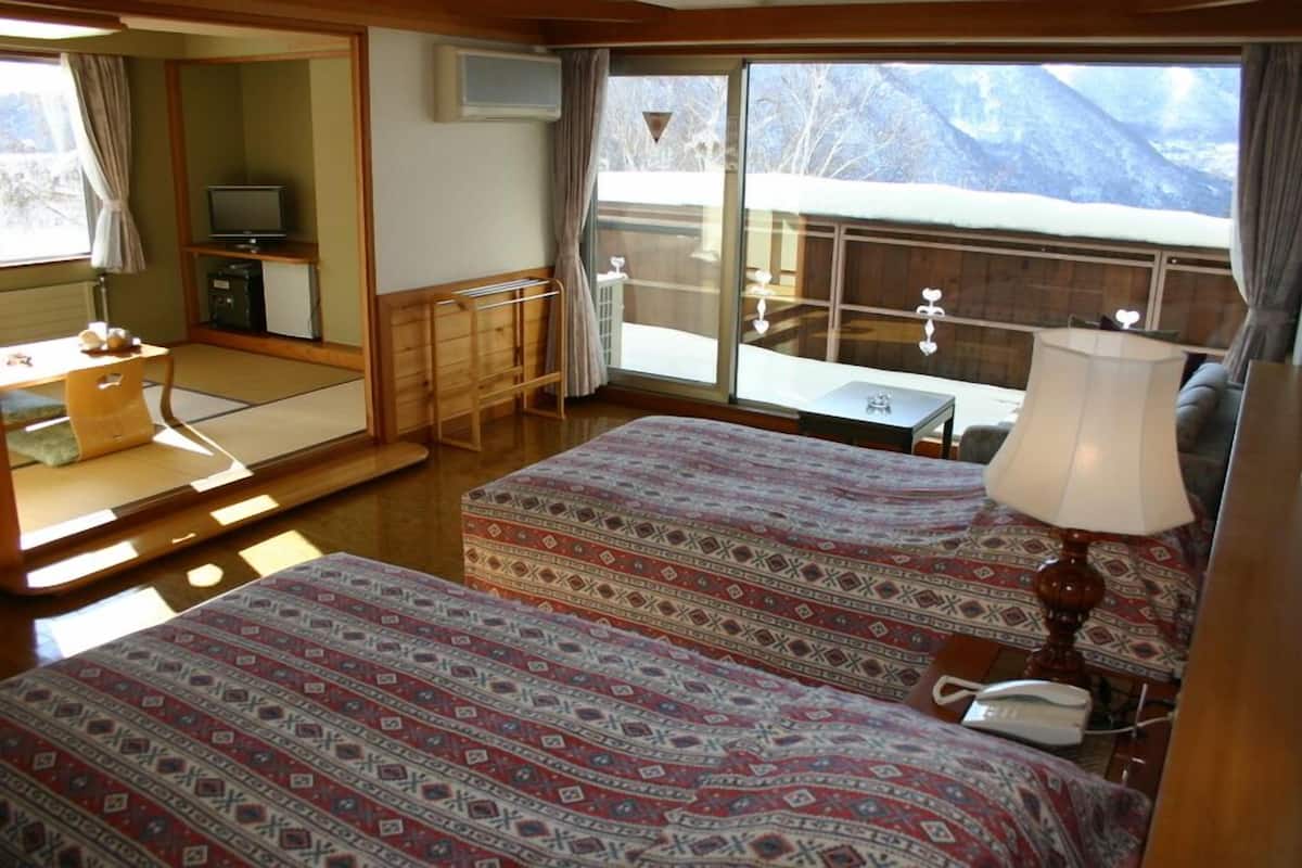 Une chambre avec deux lits, un bureau, une chaise, une télévision et une vue sur les montagnes.