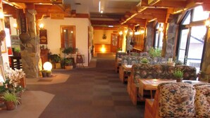 A hotel lobby with a carpeted floor, wooden furniture, and potted plants. - Hotel White Inn Kitashiga (Yamanouchi)