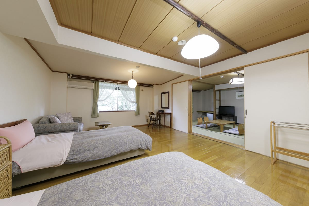 Une chambre spacieuse avec deux lits, un plafond en bois et une grande fenêtre.