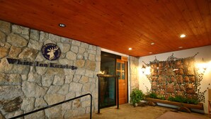 A stone wall with a sign for 'White Inn Kaskaskia' and a wooden ceiling. - Hotel White Inn Kitashiga (Yamanouchi)