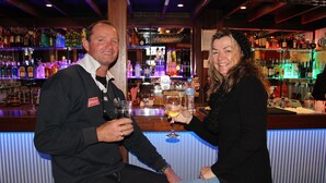 A bar with shelves of bottles and glasses, a counter, and two people sitting at the bar. - Alpine Retreat Mt Buller (Mount Buller)