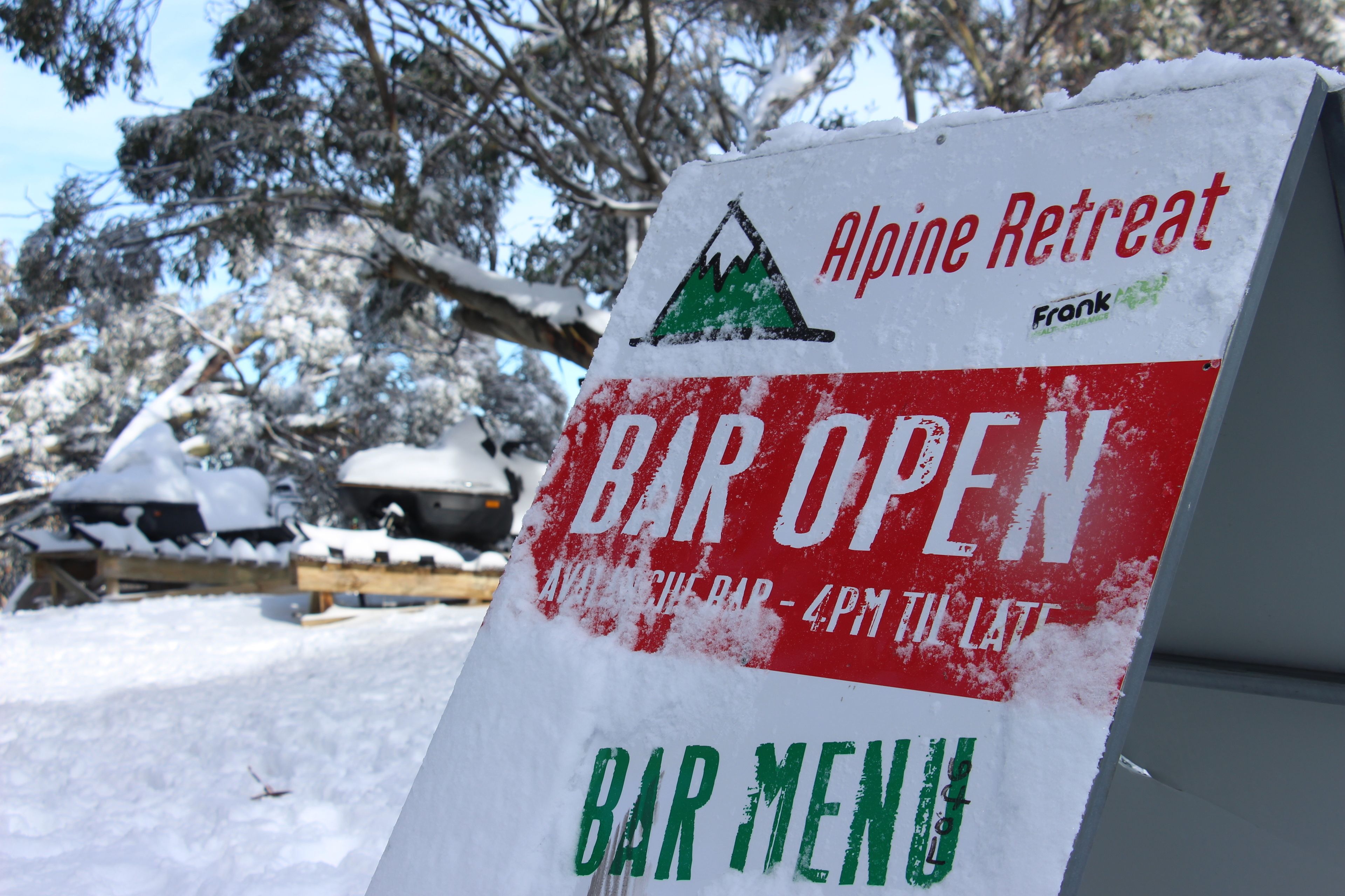 A sign for an Alpine Retreat bar open until 4 PM, with a menu listed.