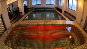 A large indoor swimming pool with a tiled floor and walls, surrounded by white walls and windows. - Alpine Retreat Mt Buller (Mount Buller)