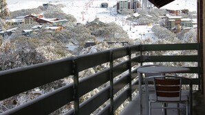 A balcony with a view of a snow-covered town, including buildings and trees. - Alpine Retreat Mt Buller (Mount Buller)