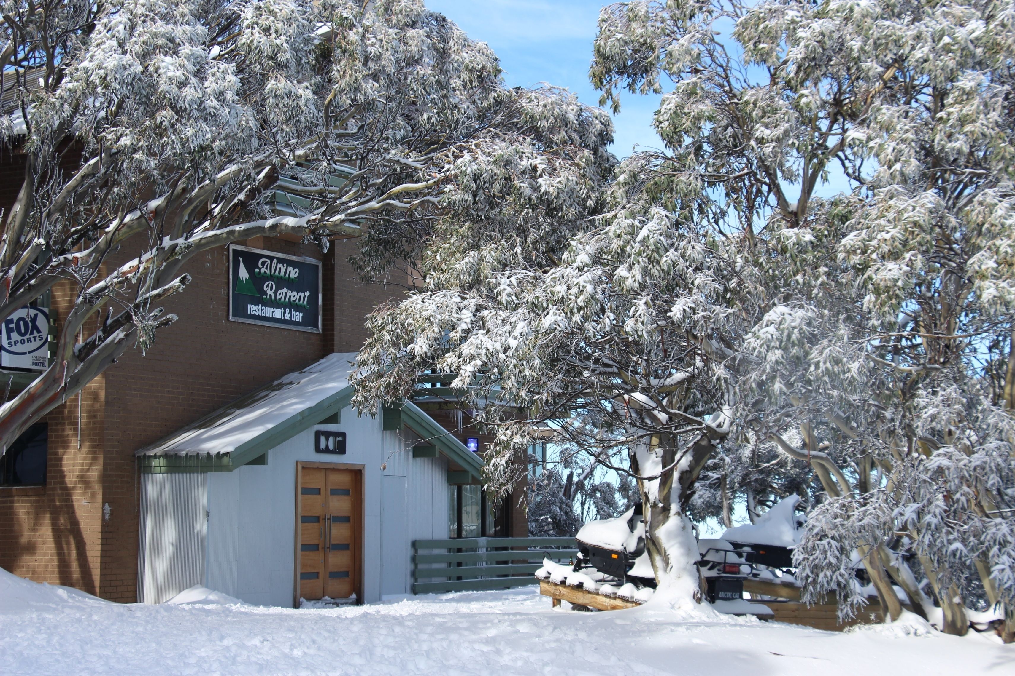 A building with a sign for 'Alpine Retreat restaurant & bar' and a wooden door.