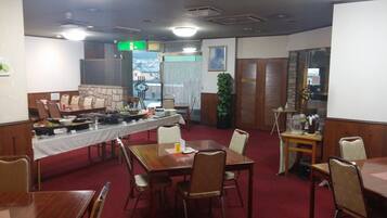 A conference room with a long table set for a meal, surrounded by chairs, and a small table with a coffee machine.