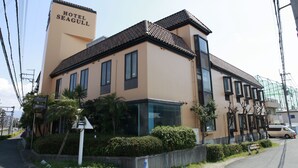 Un hotel llamado "Hotel Seagull" con un diseño moderno, que cuenta con un letrero llamativo, un tejado de baldosas y una entrada de cristal.