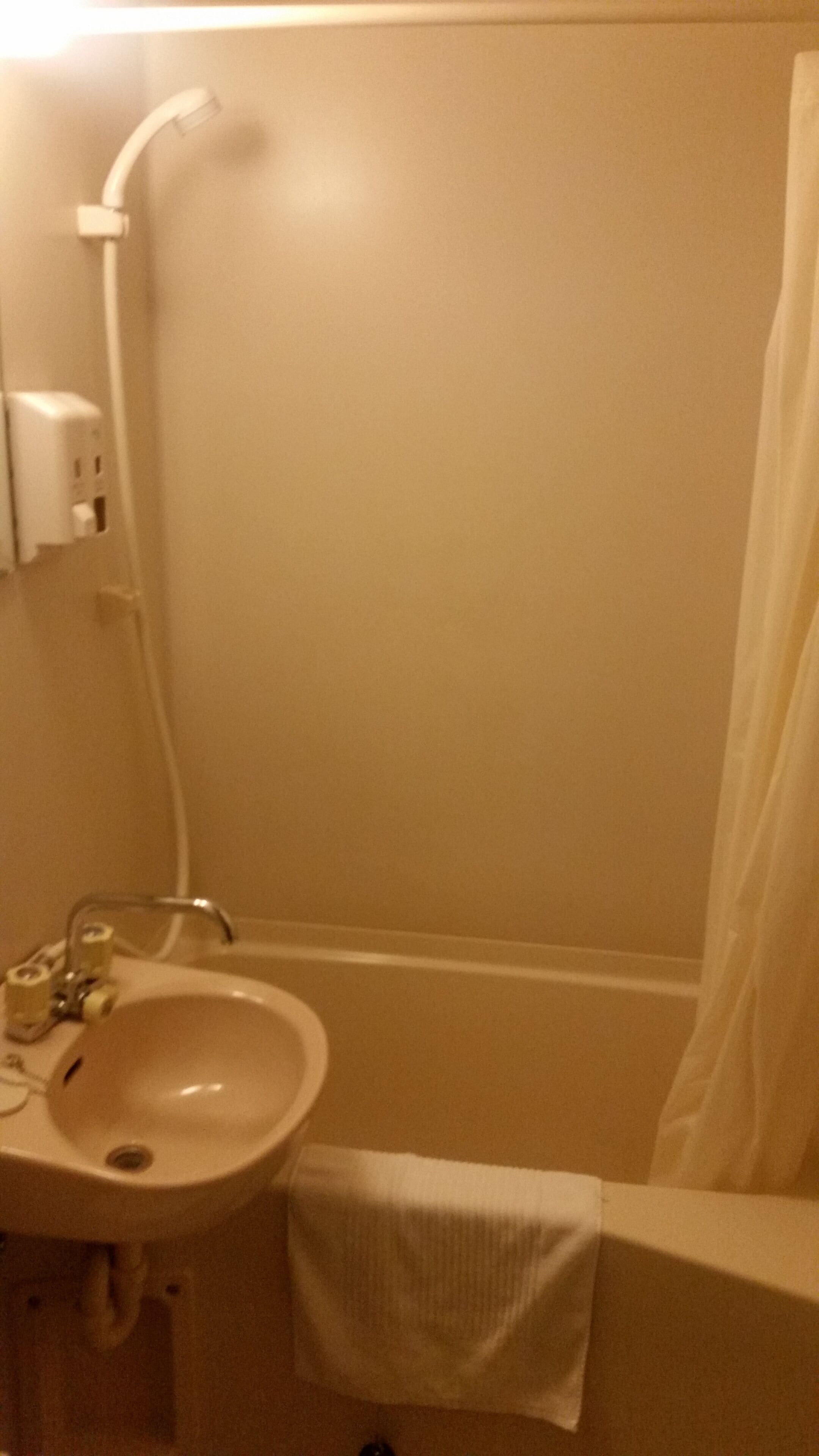 Ein Badezimmer mit Waschbecken, Dusche und einem Handtuch an der Wand.