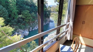 A room with a view of a river and forest through large windows, a wooden chair, and a wooden cabinet. - Ryokan Meisho Tenryukyo Onsen Ryukyotei (Iida)