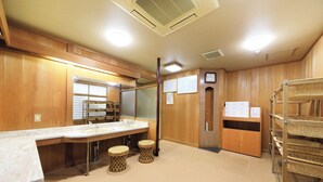 A hotel bathroom with wooden paneling, a large mirror, two sinks, a toilet, and a shelf with baskets. - Ryokan Meisho Tenryukyo Onsen Ryukyotei (Iida)