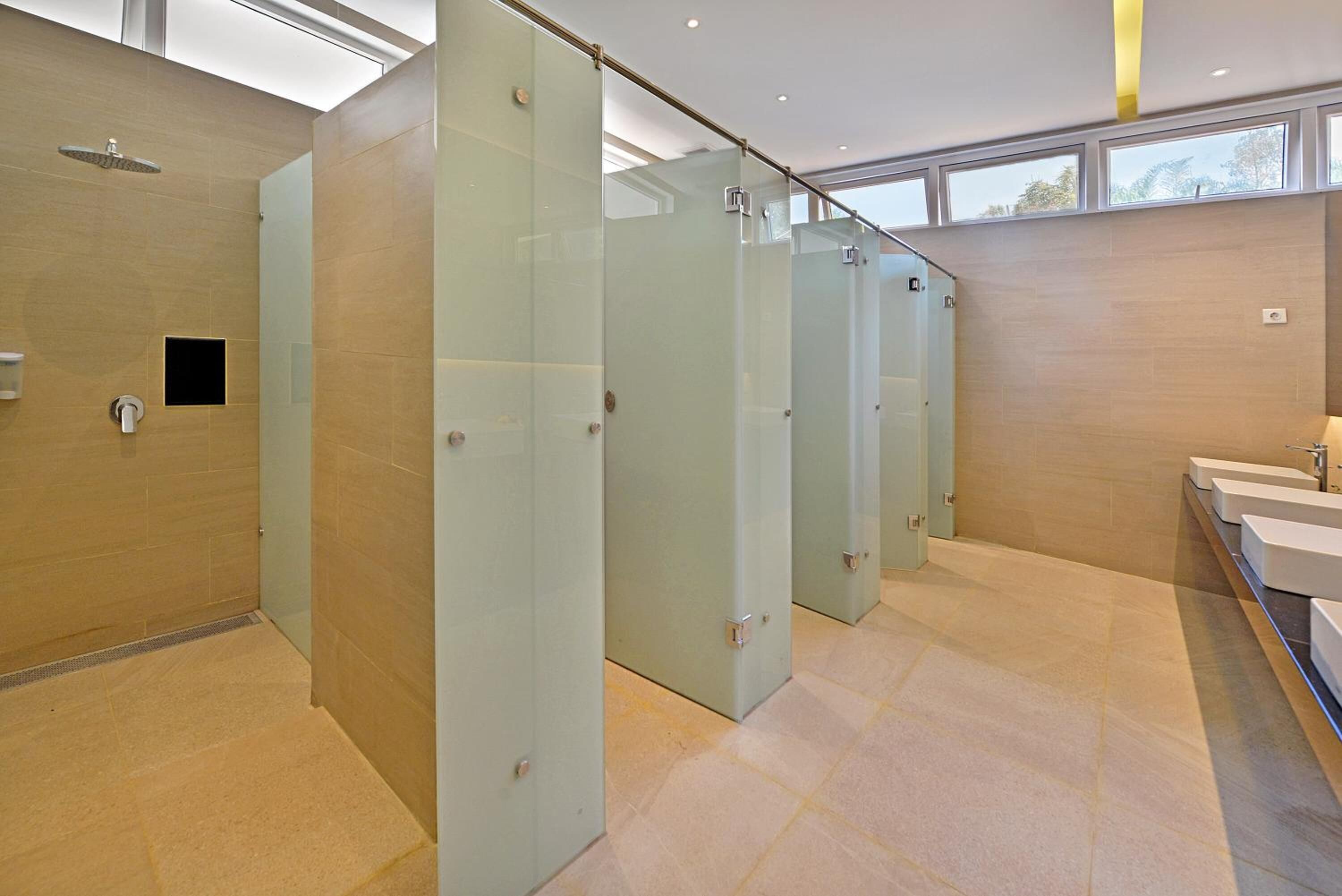 Un baño moderno con cabinas de ducha de vidrio, un secador de manos y zona de lavamanos.