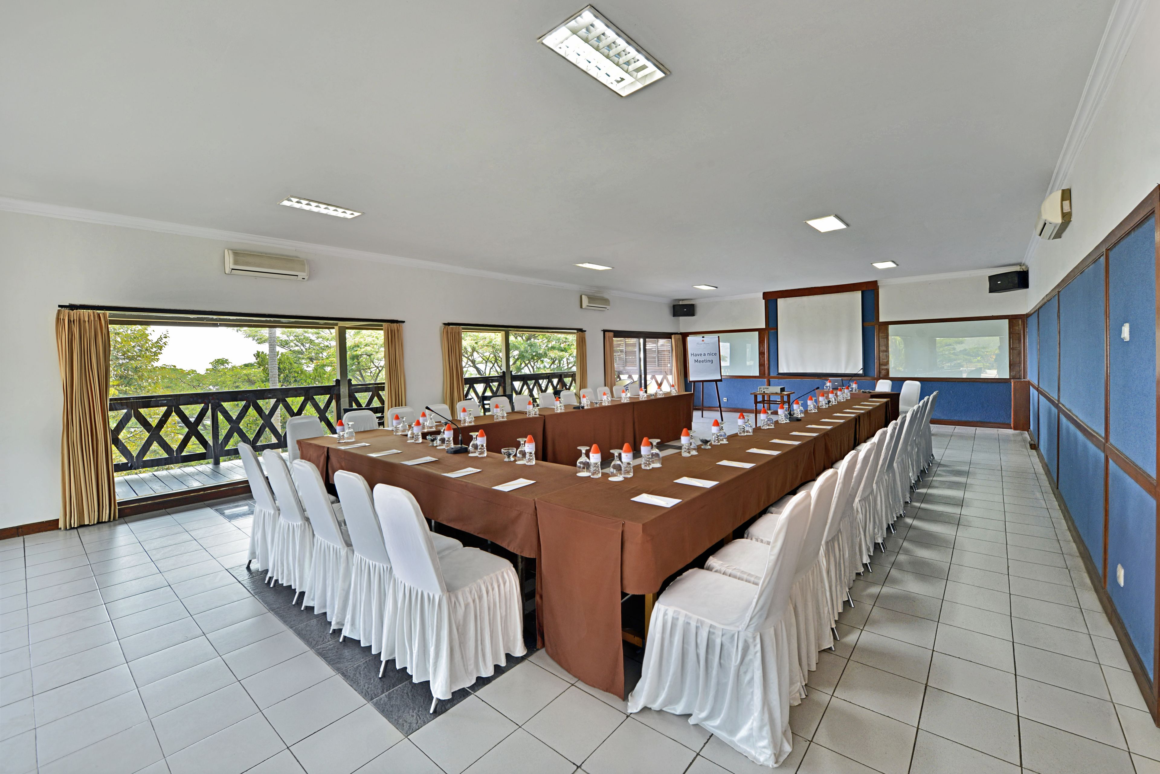 Een vergaderzaal met een lange tafel, witte stoelen en een blauwe accentmuur.
