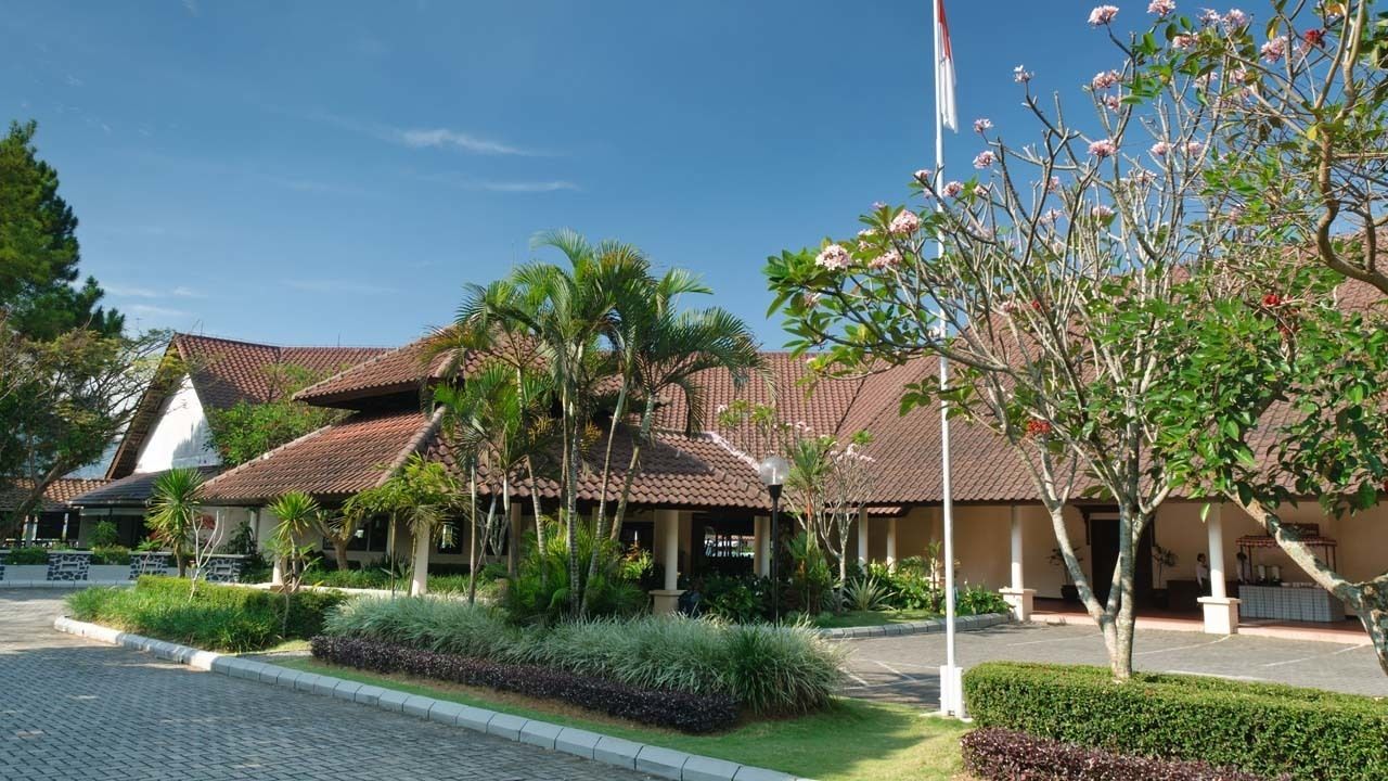 A building with a tiled roof, surrounded by well-maintained gardens and palm trees.