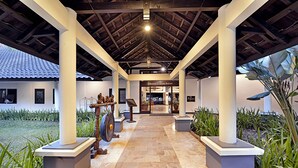 A covered walkway with stone flooring, white pillars, and a sign for the Grand Trawas Hotel. - Grand Whiz Hotel Trawas (Trawas)