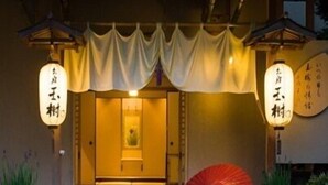 Une entrée de style japonais traditionnel, avec un parapluie rouge, des lanternes en bois et un petit sanctuaire.