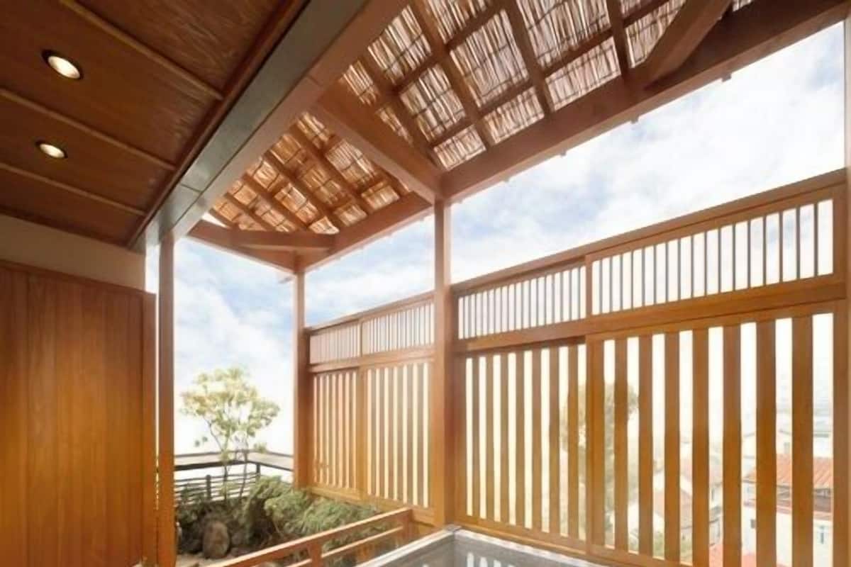 Un onsen japonés tradicional con interior de madera, una fuente termal de piedra y vistas del paisaje circundante.