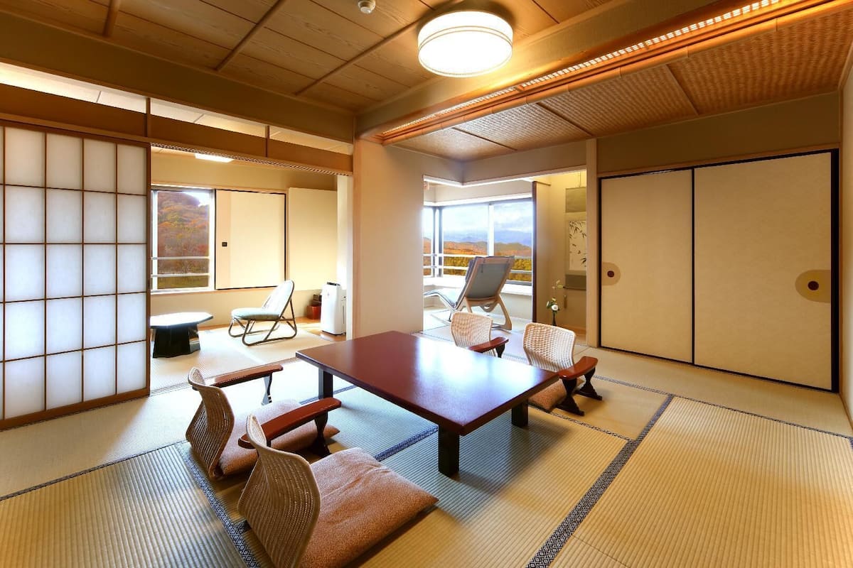 Una habitación japonesa tradicional con suelo de tatami, una mesa baja y puertas correderas shoji.